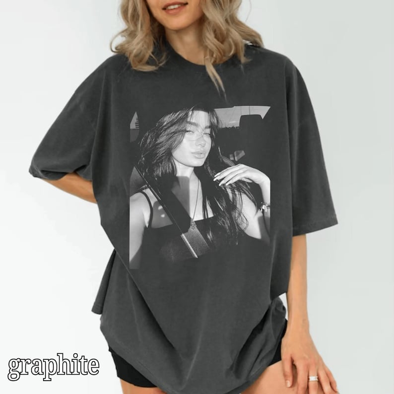 May include: Graphite-colored oversized t-shirt featuring a black and white image of a woman. The image is centered on the shirt and the word "graphite" is printed at the bottom. The shirt has short sleeves and a relaxed fit.