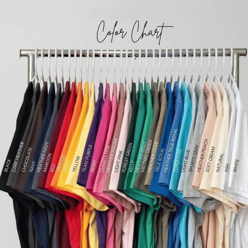 May include: A colour chart showing a range of t-shirts in various colours, including black, navy, red, yellow, pink, green, blue, and white. The shirts are hanging on a metal rack with the words "Color Chart" in cursive.