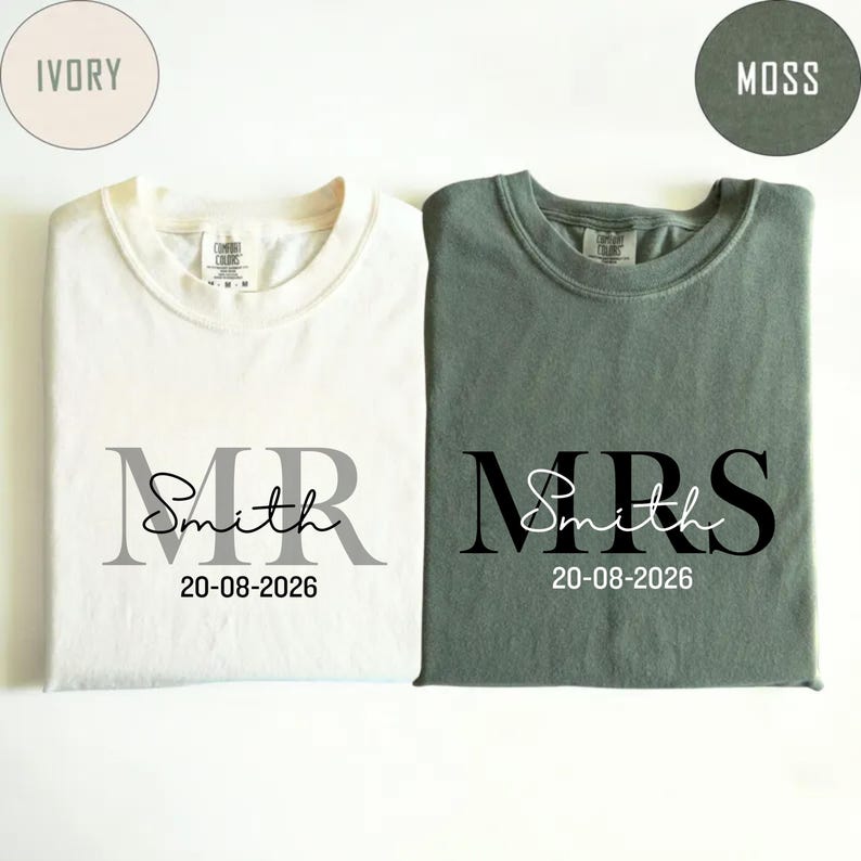 May include: Two t-shirts, one ivory and one moss green, with the words "MR Smith 20-08-2026" and "MRS Smith 20-08-2026" printed on them. The shirts are likely for a wedding or anniversary.
