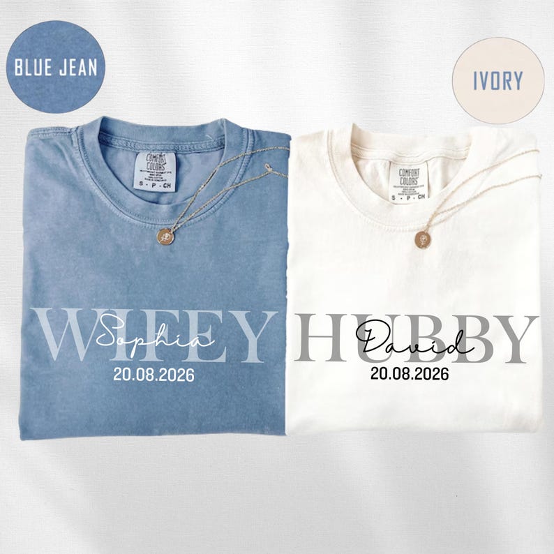 May include: Two t-shirts, one blue and one ivory, with the words "Wifey" and "Hubby" printed on them. The blue shirt has the name "Sophia" and the date "20.08.2026" printed below "Wifey". The ivory shirt has the name "David" and the date "20.08.2026" printed below "Hubby".