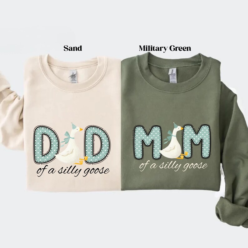 May include: Two sweatshirts, one sand-colored and one military green, each featuring a whimsical design. The sand-colored sweatshirt says "DAD of a silly goose" and the military green sweatshirt says "MOM of a silly goose". Both designs include a goose.