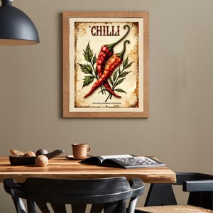 K&ouml;nnte beinhalten: Gerahmter Vintage-Print mit zwei roten Chilischoten und gr&uuml;nen Bl&auml;ttern. Das Wort "CHILLI" steht oben, mit dem Text "FOR THE BOLD AND BRAVE IN THE KITCHEN" unten. Der Druck hat ein gealtertes, abgenutztes Aussehen.