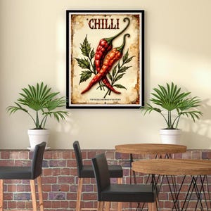 K&ouml;nnte beinhalten: Gerahmter Kunstdruck mit zwei roten Chilischoten mit gr&uuml;nen Bl&auml;ttern vor einem Hintergrund im Vintage-Stil. Das Wort "CHILLI" steht oben, mit dem Text "FOR THE BOLD AND BRAVE IN THE KITCHEN" unten.