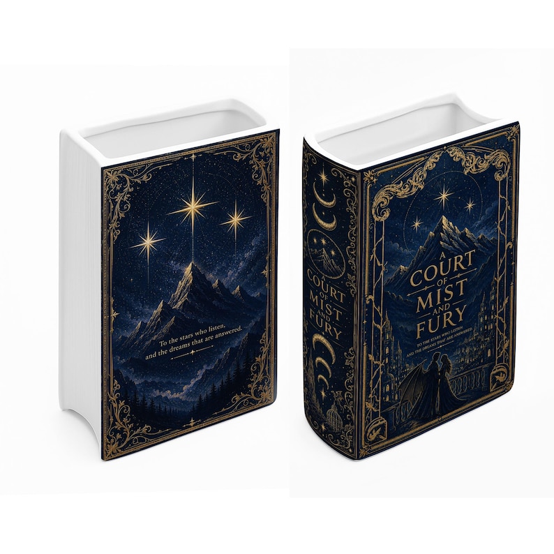 May include: A white ceramic book-shaped vase featuring a dark blue night sky illustration with gold filigree borders. The front displays a mountain peak under bright stars with the text, To the stars who listen, and the dreams that are answered.