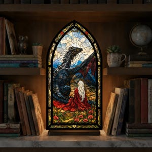 Peut inclure: Une lampe en vitrail en forme d'arche représentant un dragon sombre aux grandes ailes et une personne aux longs cheveux blancs vêtue d'une cape rouge. L'illustration est sur fond de ciel bleu et de fleurs rouges, encadrée de métal noir.