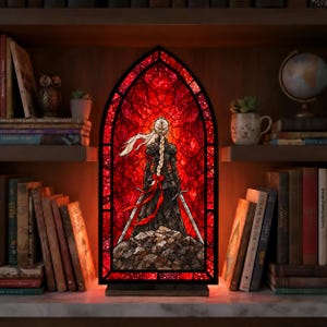 May include: An arched stained glass lamp featuring a figure with long braided hair in dark armor standing on a rocky surface against a vibrant red background. The lamp is framed in black and sits on a rectangular base between two bookshelves.