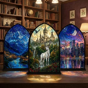 May include: Three arched stained glass panels. Each panel shows a different scene: a mountain range under a starry sky, a castle with a deer, and a cityscape at sunset. The panels are displayed on a wooden surface.