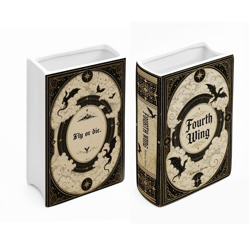 May include: A white ceramic book-shaped vase featuring black and cream illustrations of dragons, clouds, and stars. One side displays the text 'Fly or die.' while the other side features the title 'Fourth Wing' by Rebecca Yarros in black lettering.