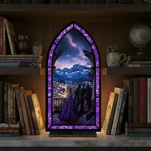 May include: A decorative stained glass window depicting a couple on a balcony, with a city and mountains under a starry sky. The window has a purple mosaic border and is lit from behind, creating a warm glow.