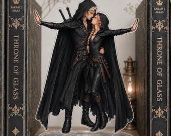 Peut inclure: Un présentoir en acrylique transparent représentant deux personnages vêtus de capes à capuche noires et d'équipements en cuir, debout l'un contre l'autre. L'homme a des cheveux clairs courts et deux épées, la femme a une longue tresse blonde.