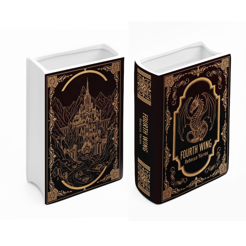 Puede incluir: Jarr&oacute;n de cer&aacute;mica blanca con forma de libro, con dise&ntilde;o negro y dorado. Un lado presenta un castillo, el otro un drag&oacute;n. El texto "FOURTH WING Rebecca Yarros" es visible. Un objeto decorativo para el hogar.