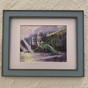 May include: A framed painting depicting a coastal landscape with a multi-domed building nestled among green hills and trees. The scene features a body of water in the foreground with white birds, illuminated by light rays. The initials E.S. are visible.
