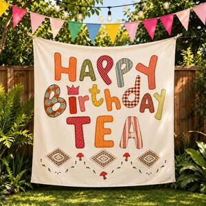May include: A cream-colored fabric banner featuring the colorful, patterned, appliqued text Happy Birthday TEA. The design includes small red mushroom illustrations and brown diamond-shaped accents along the bottom edge of the banner.