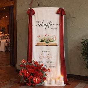 May include: A cream-colored banner with burgundy ribbons and text that reads "A New Chapter Begins." Below the text is an illustration of an open book with flowers. The banner welcomes guests to Emily's bridal shower on September 21st.