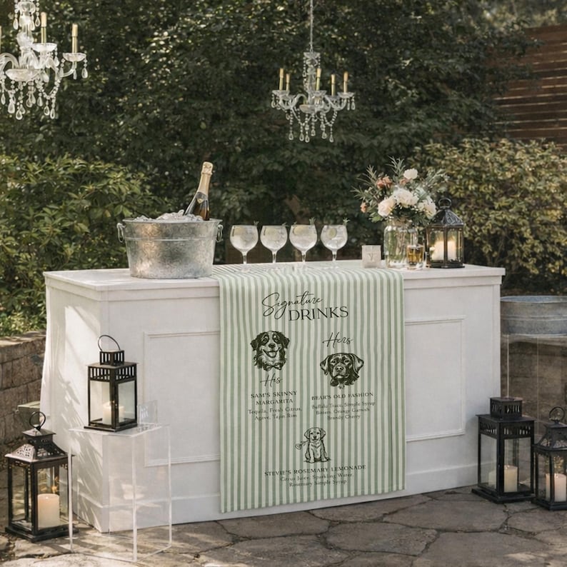 Peut inclure: Un bar ext&eacute;rieur blanc avec un chemin de table &agrave; rayures vertes et blanches affichant des illustrations de chiens et des noms de boissons. Le bar est &eacute;quip&eacute; de verres, d'une bouteille de champagne dans un seau &agrave; glace et de lanternes. Des lustres en cristal sont suspendus.