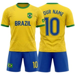 Op de afbeelding: Een geel en blauw Brazilië voetbaltenue. Het shirt heeft "BRAZIL" op de borst en een schildlogo. De blauwe shorts tonen het nummer "10" en een Braziliaanse vlag. De achterkant van het shirt heeft "OUR NAME" en het nummer "10".