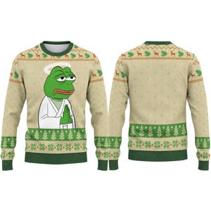 May include: A beige long-sleeve crewneck jumper featuring a green frog character with a white halo and robe in a prayer pose on the front. The garment includes a repeating pattern of green deer, frogs, and pine trees across the chest and hem.