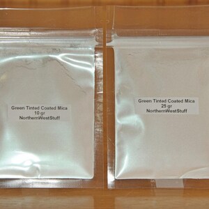 May include: Two clear plastic bags containing green-tinted coated mica powder. The bags have labels that read "Green Tinted Coated Mica" and "NorthernWestStuff". One bag contains 10 grams, the other 25 grams of powder.