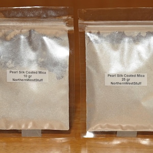 May include: Two clear plastic bags filled with a pearlescent powder labeled "Pearl Silk Coated Mica." One bag contains 10 grams, the other 25 grams. The text "NorthernWestStuff" is also printed on the labels.