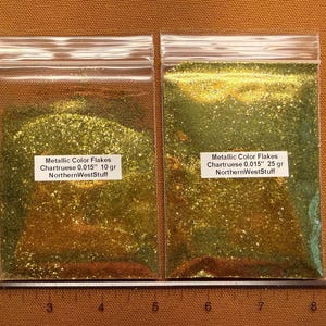 May include: Two clear plastic bags filled with chartreuse metallic color flakes. The bags have white labels with text that reads "Metallic Color Flakes Chartruese 0.015" 10 gr NorthernWestStuff" and "Metallic Color Flakes Chartruese 0.015" 25 gr NorthernWestStuff".