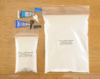 May include: Two clear plastic bags filled with white acrylic resin powder, one labeled 25 grams and the other 100 grams. Two tubes of glue and various applicator tips are also visible. The text on the bags reads "Acrylic Resin Powder 325 Mesh".