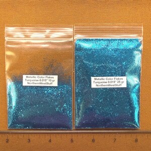 May include: Two clear plastic bags filled with turquoise metallic color flakes. The bags have white labels that read "Metallic Color Flakes Turquoise 0.015" 10 gr NorthernWestStuff" and "Metallic Color Flakes Turquoise 0.015" 25 gr NorthernWestStuff".