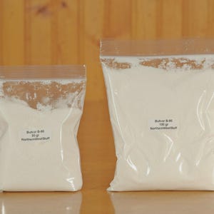 May include: Two clear plastic bags filled with white powder. The smaller bag is labeled "Butvar B-90 50 gr NorthernWestStuff." The larger bag is labeled "Butvar B-90 100 gr NorthernWestStuff." Both bags are sealed with a brown strip.