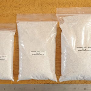 May include: Three clear plastic bags filled with white dolomite. The bags are labeled with the weight of the contents: 200 grams, 400 grams, and 800 grams. The text "Dolomite, Very Coarse" and "NorthernWestStuff" are also visible.
