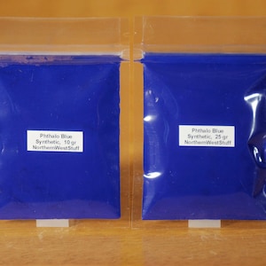 May include: Two clear plastic bags filled with vibrant blue pigment powder. The bags have white labels with the text "Phthalo Blue Synthetic" and the weight, 10 gr and 25 gr. The product is from NorthernWestStuff.