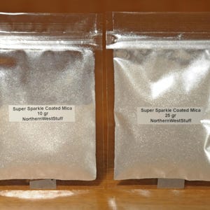 May include: Two clear plastic bags filled with shimmering, white Super Sparkle Coated Mica. One bag is labeled "10 gr" and the other "25 gr". Both bags have a label that reads "NorthernWestStuff".