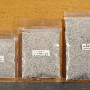 May include: Three clear plastic bags filled with gray grog. Each bag has a white label with text indicating the grog type, mesh size, and weight: 50 grams, 100 grams, and 200 grams. A ruler is at the bottom.