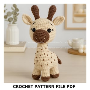 May include: A crocheted giraffe toy in cream and brown. The giraffe has brown spots, a brown snout, and large black eyes. The text "CROCHET PATTERN FILE PDF" is at the bottom of the image. The toy is handmade and appears soft.
