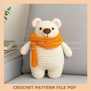 May include: A crocheted polar bear with a brown nose and black eyes, wearing an orange scarf. The bear is sitting on a gray couch. The text "CROCHET PATTERN FILE PDF" is at the bottom.