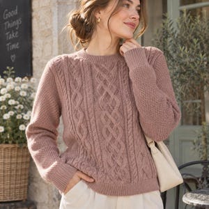 May include: A dusty rose long-sleeved sweater featuring a central vertical cable knit pattern flanked by textured honeycomb knit panels on the sides, finished with a ribbed crew neckline, ribbed cuffs, and a ribbed hemline at the waist.