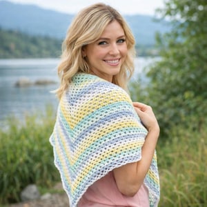 Peut inclure: Un châle en crochet aux couleurs pastel avec des rayures horizontales jaunes, bleues et blanches. Le châle est drapé sur les épaules, créant une forme triangulaire. Le motif ajouré ajoute une touche délicate à cet accessoire.