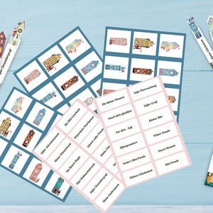 May include: A collection of Christmas-themed paper goods, including cards with house illustrations and labels with German text. The cards are arranged on a light blue surface. The image includes decorative bookmarks with house designs and the text "Mini Freude" and "S&uuml;&szlig;er Dezembergru&szlig;".