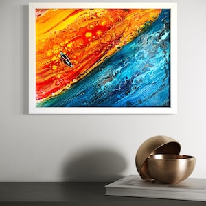 Könnte beinhalten: Abstrakter Kunstdruck in einem weißen Rahmen. Das Kunstwerk zeigt eine lebendige Mischung aus Farben, wobei feurige Orangen und Rot mit kühlen Blautönen kontrastieren. Ein kleines Boot ist im Kunstwerk zu sehen und verleiht dem Stück ein Gefühl von Maßstab und Tiefe.