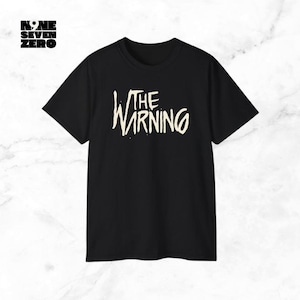 Pode incluir: Camiseta preta de gola redonda com a frase "THE WARNING" em uma fonte desgastada em branco sujo na frente. O canto superior esquerdo apresenta o texto "N9NE SEVEN ZERO" em uma fonte empilhada e em bloco. Estilo simples e casual.