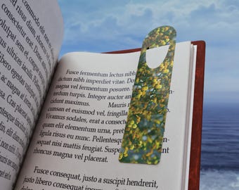 May include: A colorful bookmark with a floral pattern is inserted into a book. The bookmark has a rectangular shape with a curved top and a cutout. The book is open, revealing printed text.