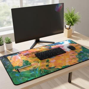 May include: A desk setup featuring a large floral-patterned mousepad with a black keyboard, mouse, and monitor. A small notebook and pen holder are also on the desk. The mousepad has a vibrant design with orange and yellow flowers.