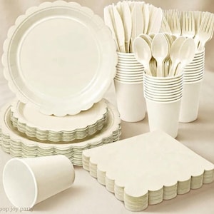 May include: A set of cream-colored disposable party supplies including scalloped-edge paper plates, paper cups, and plastic cutlery consisting of forks, spoons, and knives. The collection features a uniform solid color and scalloped edges.