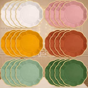 May include: A set of round paper plates with scalloped edges, arranged in six groups of four. The colors include white, light pink, mustard yellow, terracotta orange, sage green, and dark forest green, each featuring a thin gold-colored rim.