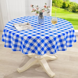 May include: A round table covered with a blue and white checkered tablecloth. On the table sits a clear glass vase containing pink and white flowers, a clear glass of amber liquid, and an open book with white pages and black text.
