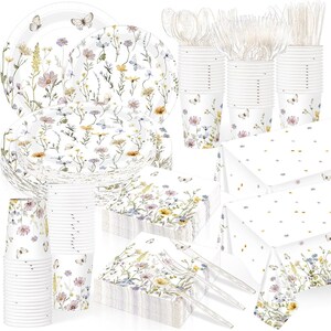 May include: A party supply set featuring white paper plates, cups, and napkins decorated with a watercolor wildflower and butterfly pattern. The set includes clear plastic forks, knives, and spoons, along with a white tablecloth with gold dots.