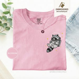 宇宙アライグマTシャツ、刺繍入りおもしろアライグマシャツ、かわいい宇宙動物Tシャツ、コンフォートカラーシャツ、アライグマ好きへのギフト、かわいい動物シャツ Blossom