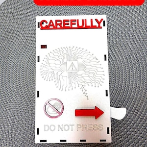 May include: A white card with the text "CAREFULLY" and "DO NOT PRESS". The card features a brain-like circuit design, a red arrow, and a red banner that says "Adult Humor".
