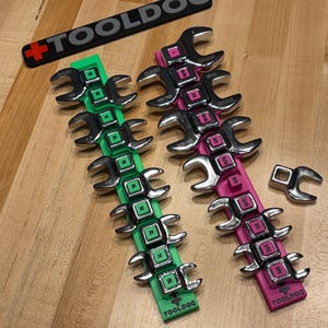 May include: A set of chrome wrenches in green and pink holders, with the "TOOLDOC" logo. The wrenches are arranged in rows, with size markings on each. A separate wrench is also visible.