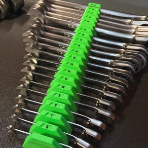 May include: A set of chrome wrenches arranged in a green organizer. The wrenches are labeled with sizes from 6 to 19. The tools are neatly organized, suggesting a focus on precision and organization for automotive or mechanical work.