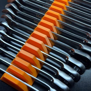 May include: A set of shiny, silver wrenches arranged in an orange organizer. The wrenches are angled, with the sizes marked in millimeters. The organizer is a bright orange color, and the background is black.