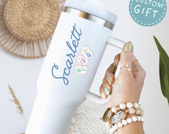 May include: A white stainless steel tumbler with a handle and a white lid. The tumbler features the name Scarlett in blue cursive script, accompanied by three small mahjong tile illustrations. A blue circular badge reads CUSTOM GIFT.